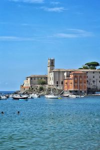 Sea by buildings against blue sky