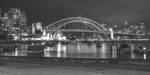 Illuminated bridge over river in city at night