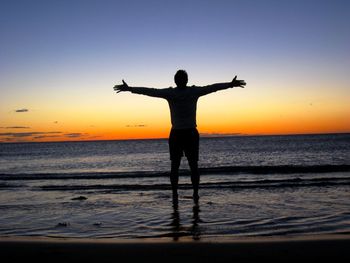 Silhouette of people on beach at sunset