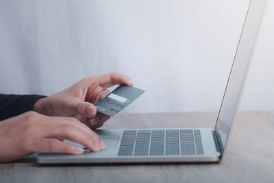 Cropped image of man using laptop on table