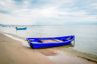 Boat moored on shore against sky