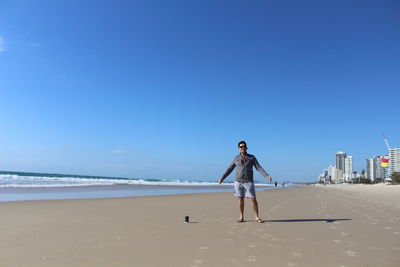 Man standing on beach against clear blue sky