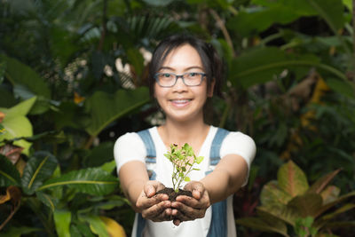 Portrait of smiling young woman holding plant