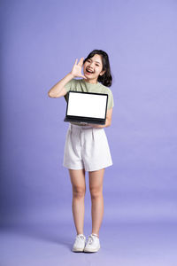 Portrait of young woman using mobile phone against blue background