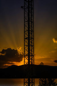 Silhouette electricity pylon against sky during sunset