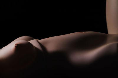 Midsection of woman lying down against black background