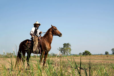 Full length of horse riding on field against sky