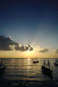 Silhouette boats in sea against sky during sunset