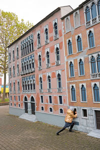 Woman walking on footpath by building in city