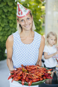 Portrait of mid adult woman holding bowl of crayfish
