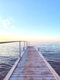 Pier over sea against sky during sunset
