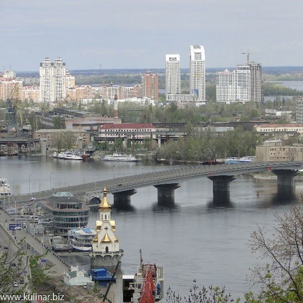 architecture, built structure, building exterior, water, city, cityscape, river, transportation, high angle view, connection, bridge - man made structure, residential building, tree, sky, waterfront, nautical vessel, city life, residential district, residential structure, mode of transport