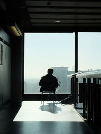 Rear view of silhouette man sitting against clear sky