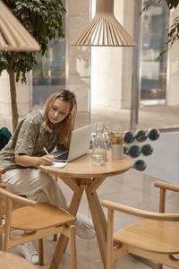 Woman writing in diary while sitting at cafe