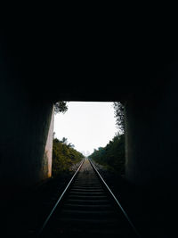 Railroad tracks in tunnel against clear sky