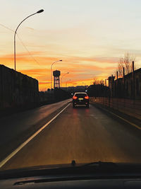 Cars on road against sky during sunset