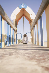 Rear view of woman sitting on railing