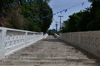 Walkway by bridge against sky