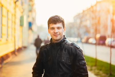 Portrait of smiling man standing on footpath against sky