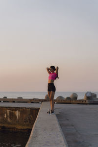 Woman standing on sea shore against sky