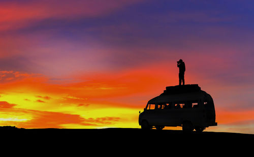 Silhouette statue on field against orange sky