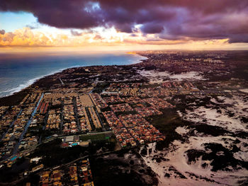 Aerial view of sea and buildings against sky during sunset