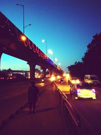 Man on illuminated bridge against sky at night