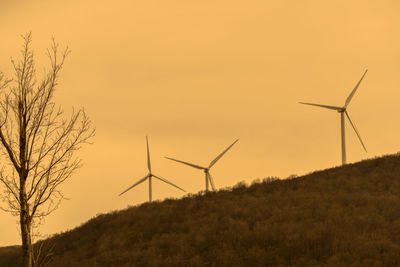 Windmill on field against sky at sunset