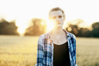 Portrait of young woman standing against sky during sunset