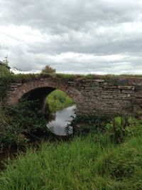 Arch bridge against cloudy sky