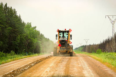 Traveling on a gravel road behind a grader.