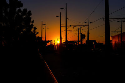Silhouette railroad tracks against sky during sunset