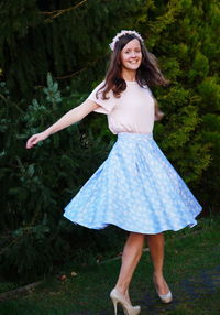 Portrait of smiling young woman with arms outstretched standing on field