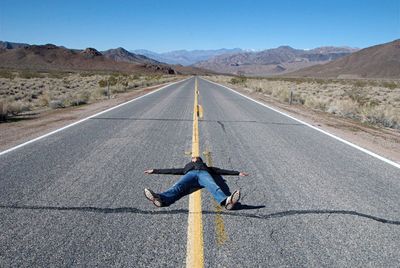 Man lying on road in desert