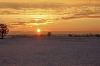 Scenic view of snow covered landscape against sky during sunset