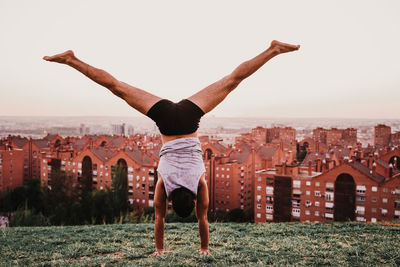 Rear view of man doing handstand on mountain against sky 