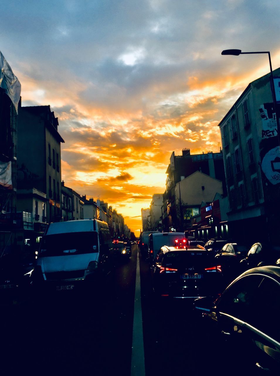 TRAFFIC ON CITY STREET AGAINST SKY DURING SUNSET