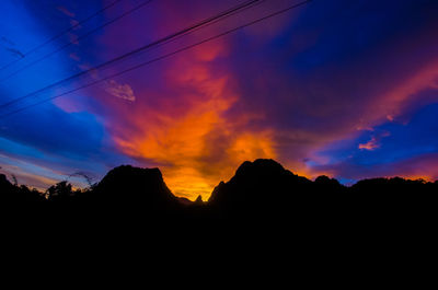 Silhouette of mountain range against cloudy sky