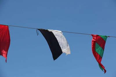 Low angle view of flags hanging from rope against clear sky