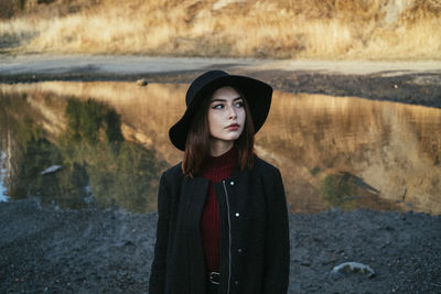 Portrait of beautiful young woman standing by water