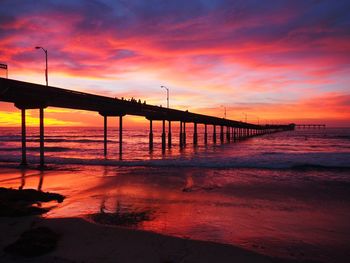 Pier over sea against sky during sunset