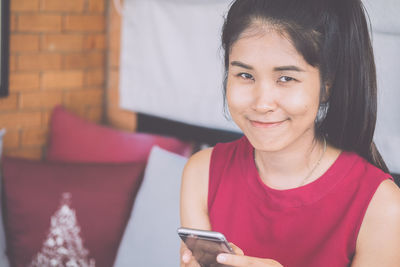 Portrait of smiling woman using mobile phone at home