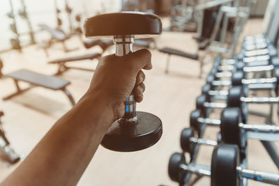 Cropped man exercising with dumbbell in gym