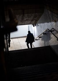 Rear view of silhouette man walking on staircase