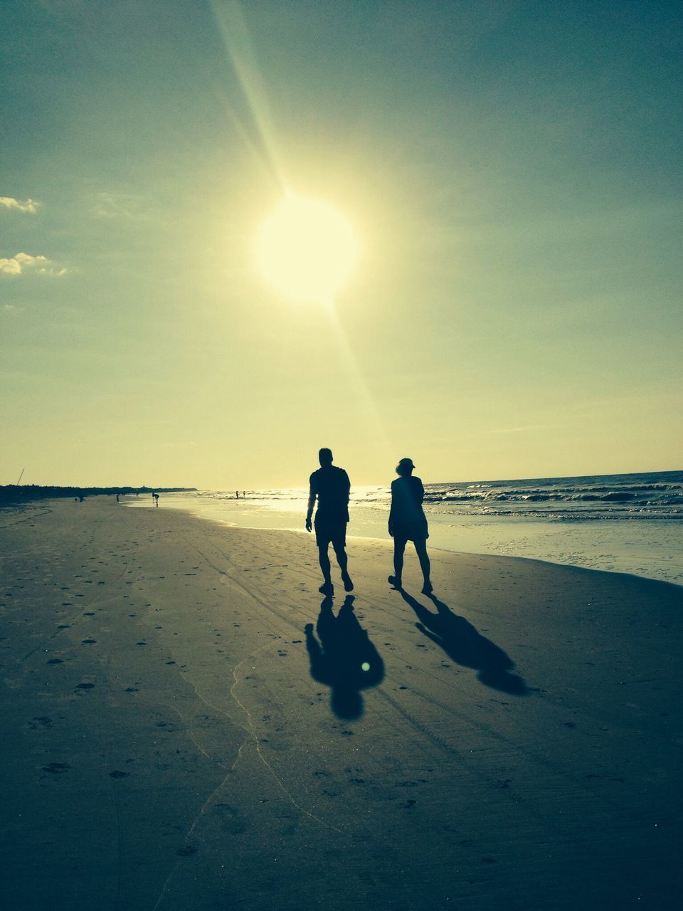 beach, sea, water, shore, sun, horizon over water, silhouette, leisure activity, lifestyles, sand, togetherness, full length, sunset, sunlight, walking, men, sky, vacations