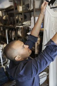 Man arranging clothes in coathangers at fashion store