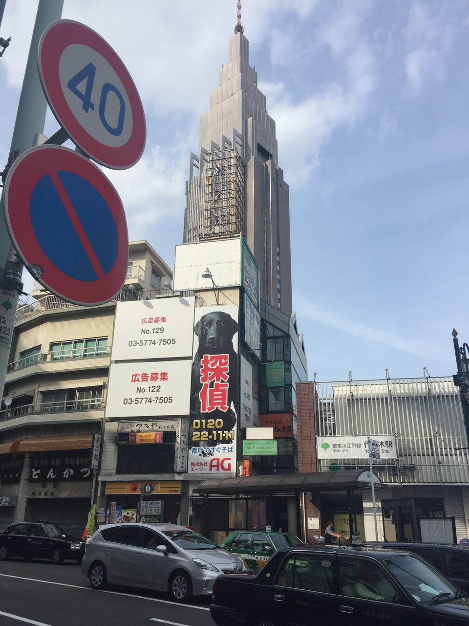 building exterior, architecture, built structure, text, transportation, car, city, land vehicle, communication, western script, mode of transport, road sign, sky, tower, street, low angle view, travel, information sign, non-western script, tall - high