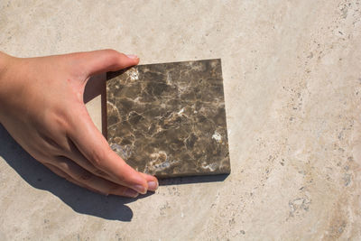 Cropped hand of person holding marble on floor