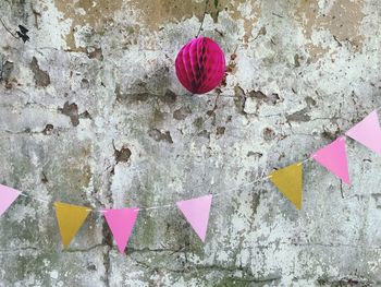 Close-up of pink and white paper hanging on wall