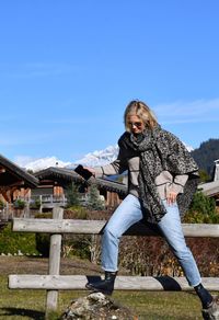 Woman balancing on rocks against blue sky